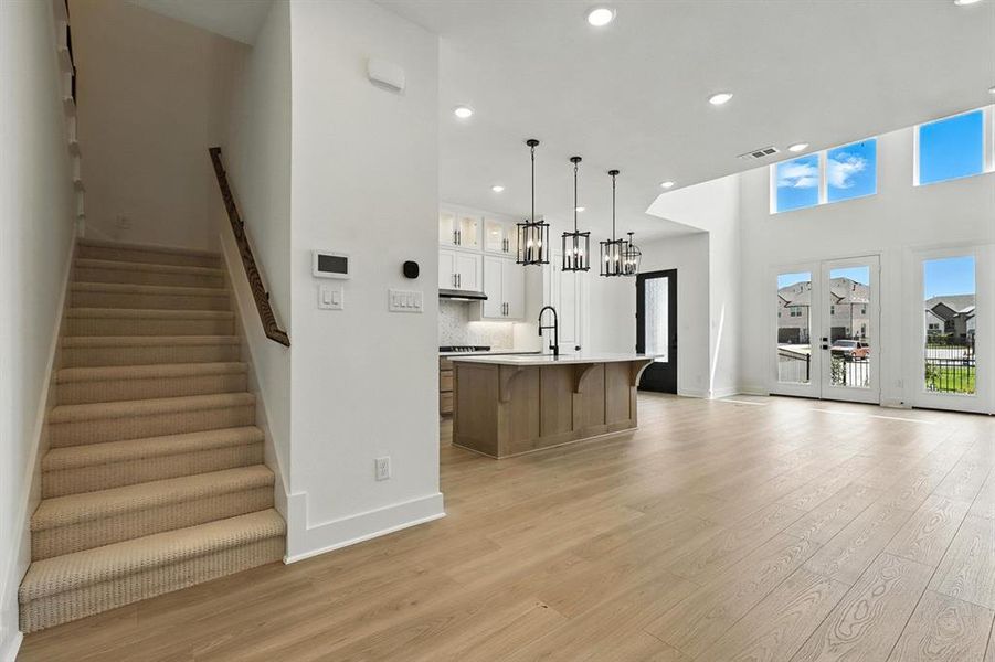 Kitchen featuring white cabinetry, hanging light fixtures, recessed lighting, an island with sink, and light wood-type flooring Kitchen featuring white cabinetry, hanging light fixtures, recessed lighting, an island with sink, and light wood-type flooring
