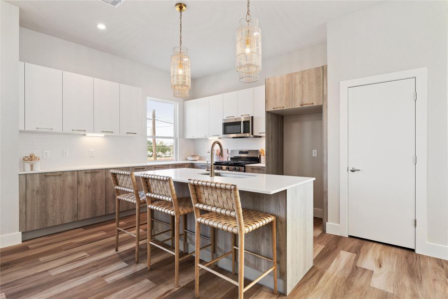 Custom pendant lighting and warm gold hardware elevate the island, with a walk in pantry discreetly positioned for everyday function.