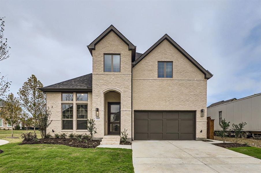 French country inspired facade featuring a garage and a front yard