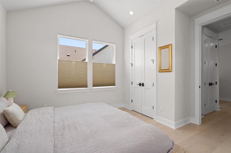 A private, naturally illuminated bedroom offers vaulted ceilings and light wood flooring. A private, naturally illuminated bedroom offers vaulted ceilings and light wood flooring.