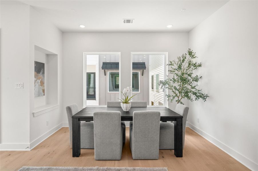 A spacious dining area framed by oversized windows, with a stylish inset nook ideal for a bar setup or curated art display.