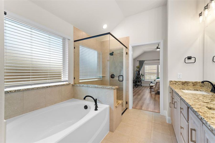 Full bathroom with lofted ceiling, ensuite bathroom, a garden tub, double vanity, and light tile patterned flooring Full bathroom with lofted ceiling, ensuite bathroom, a garden tub, double vanity, and light tile patterned flooring