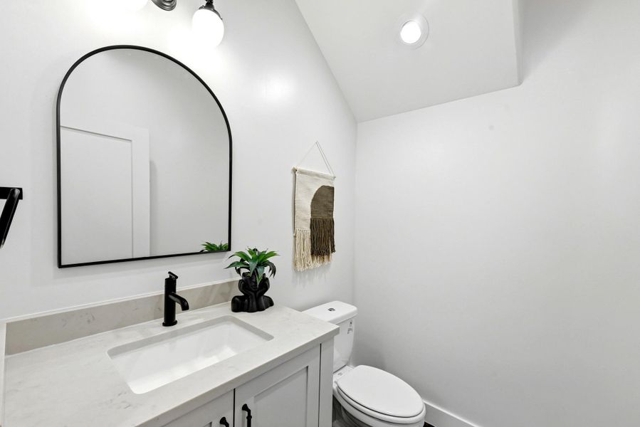 A pristine powder room featuring a modern arched mirror and elegant vanity. A pristine powder room featuring a modern arched mirror and elegant vanity.