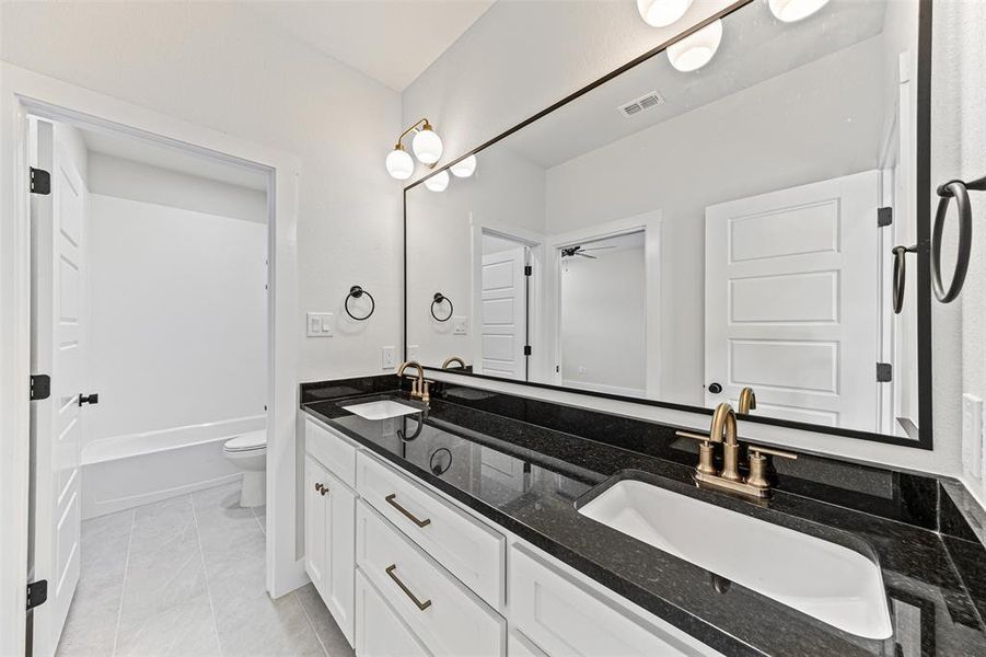 Full bathroom with double vanity, light tile patterned flooring, and a bathtub Full bathroom with double vanity, light tile patterned flooring, and a bathtub