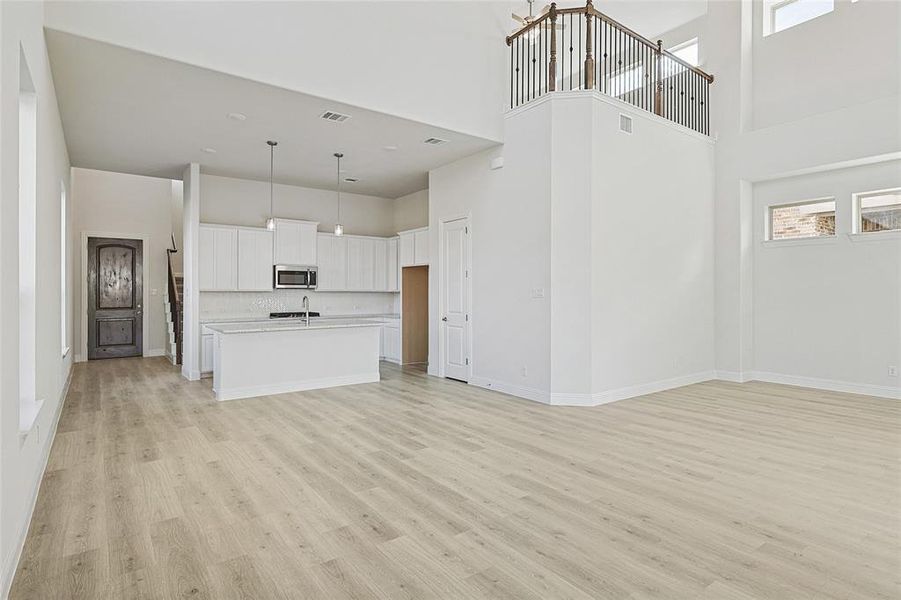 Unfurnished living room with a towering ceiling and light wood-type flooring