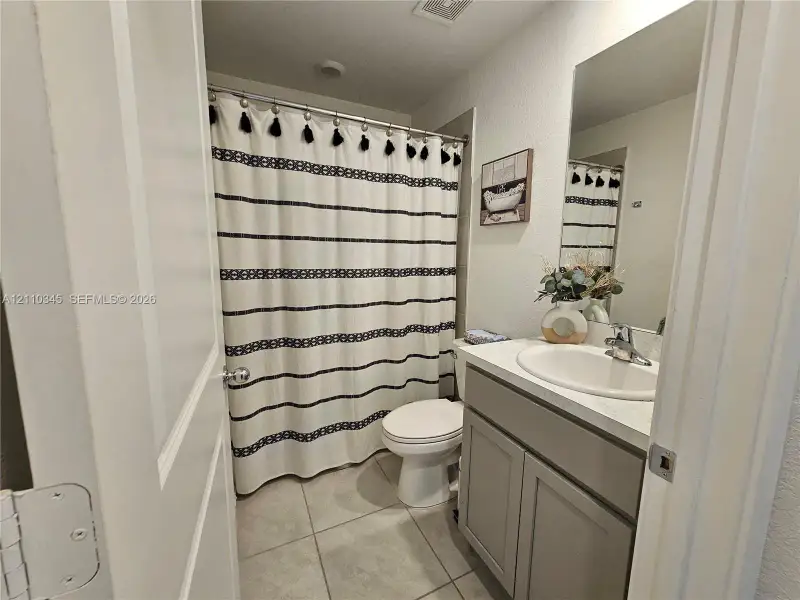 Bathroom featuring a vanity with shaker-style cabinetry, an integrated sink, a rectangular mirror, and tile flooring