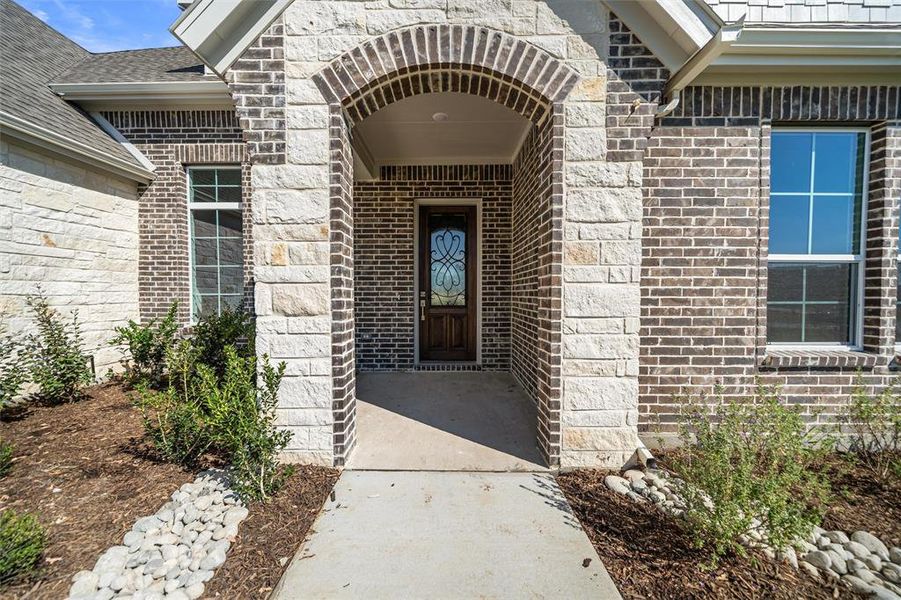 Entrance to property with brick siding and a shingled roof Entrance to property with brick siding and a shingled roof