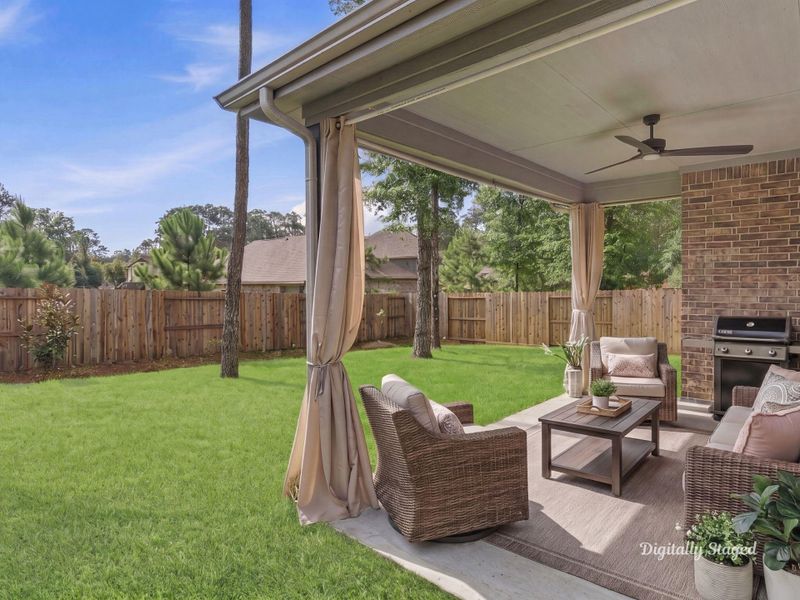 Covered back patio with a ceiling fan and plenty of room to relax or entertain. It opens directly to the spacious fenced yard and shaded, wooded surroundings. This photo has been digitally staged to illustrate the possibilities of the home's aesthetic and potential design. Some furnishings and décor shown are for visual inspiration.