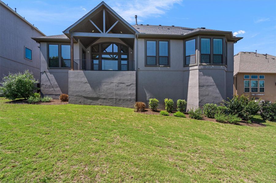 Expansive backyard featuring a manicured lawn and mature shrubs