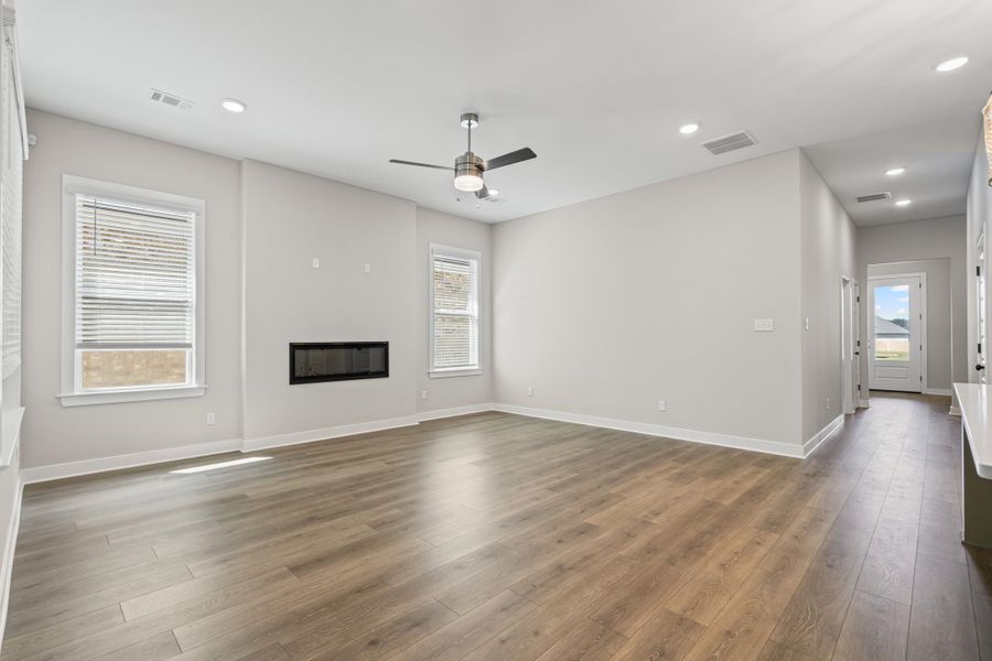 Unfurnished living room with a glass covered fireplace, light wood finished floors, recessed lighting, and ceiling fan