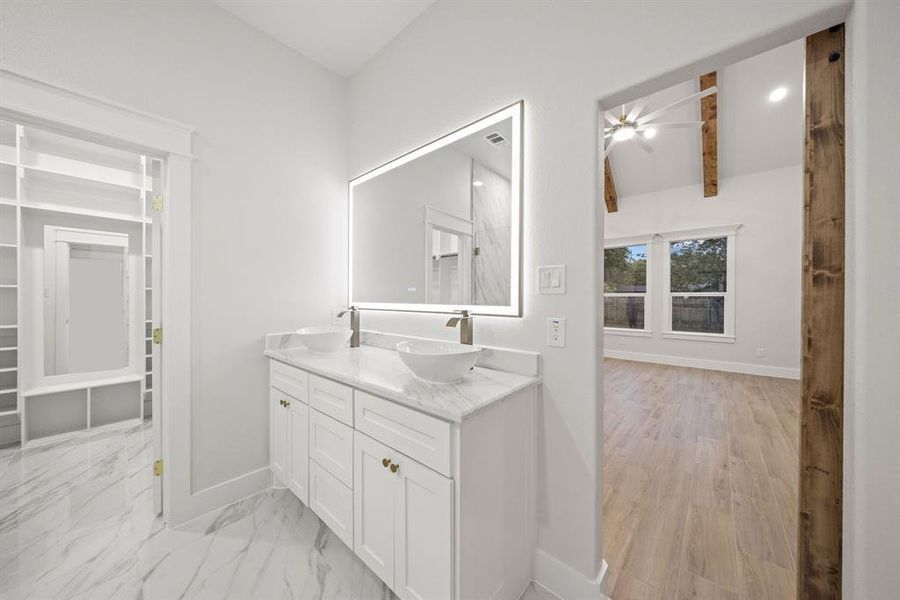 Bathroom vanity featuring dual vessel sinks, a quartz countertop, and an illuminated mirror Bathroom vanity featuring dual vessel sinks, a quartz countertop, and an illuminated mirror