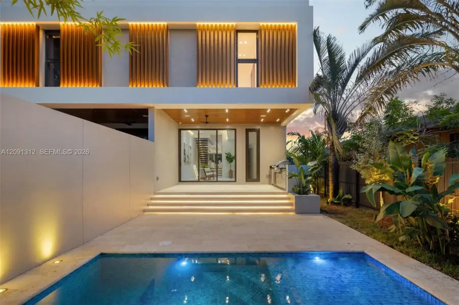 Contemporary exterior featuring vertical wood-slat accents, a covered patio with recessed lighting, stone-finish decking, and an in-ground swimming pool Contemporary exterior featuring vertical wood-slat accents, a covered patio with recessed lighting, stone-finish decking, and an in-ground swimming pool