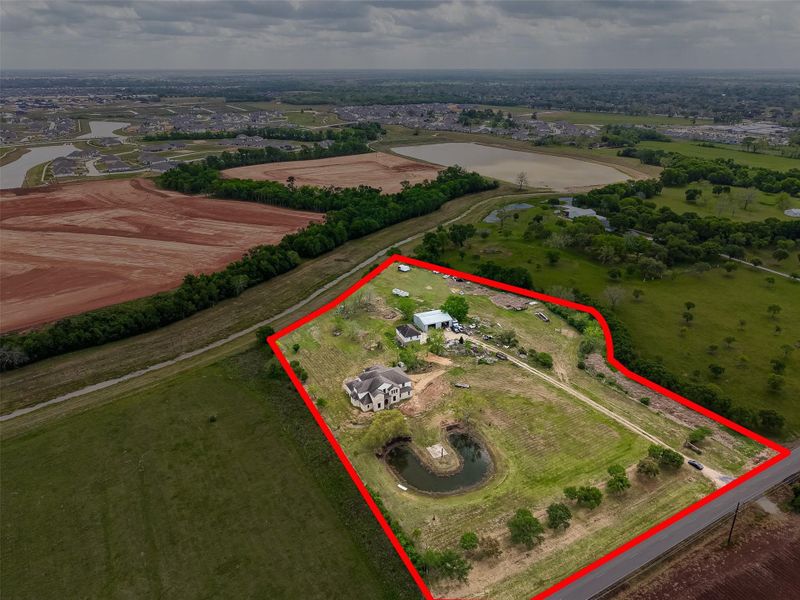 Aerial view of the property with outlined boundaries, multiple structures, and expansive rural surroundings.