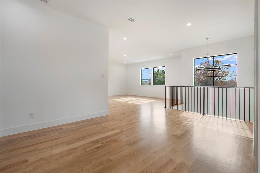 Spare room with a chandelier and light hardwood / wood-style floors