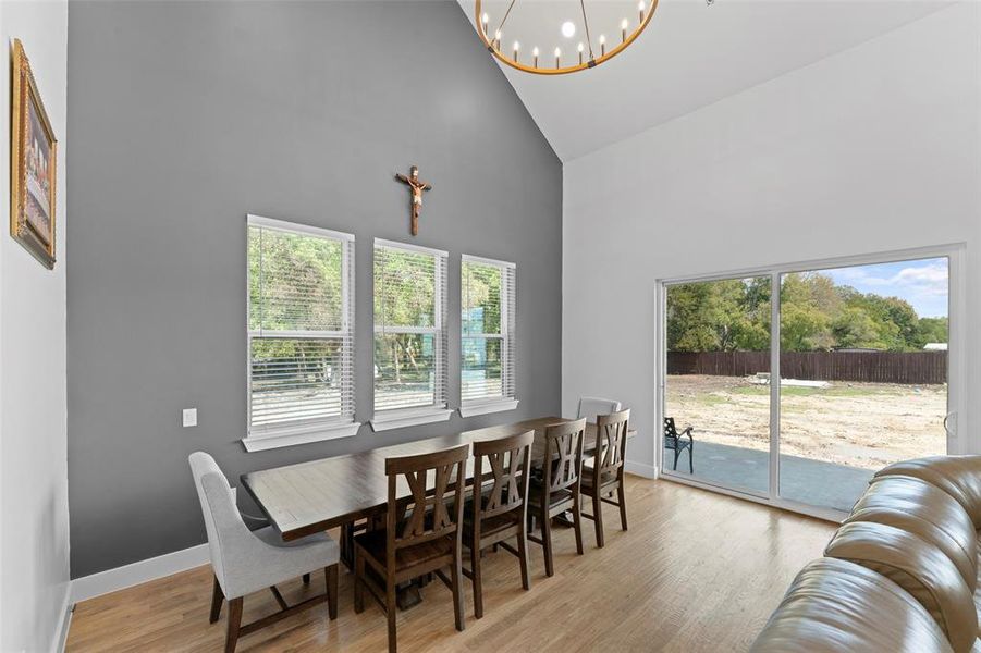Dining area with high vaulted ceiling, light wood-style floors, and a chandelier Dining area with high vaulted ceiling, light wood-style floors, and a chandelier