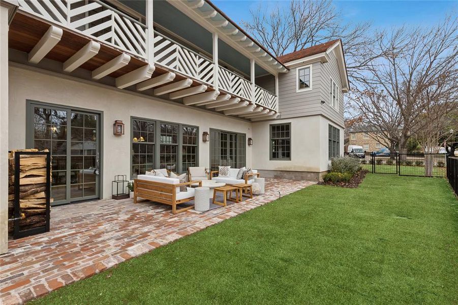 Back of property featuring a balcony, an outdoor hangout area, a gate, fence, and stucco siding