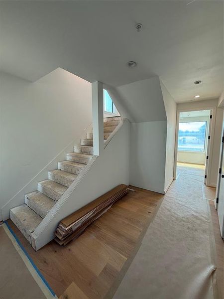 Stairs with wood finished floors and recessed lighting