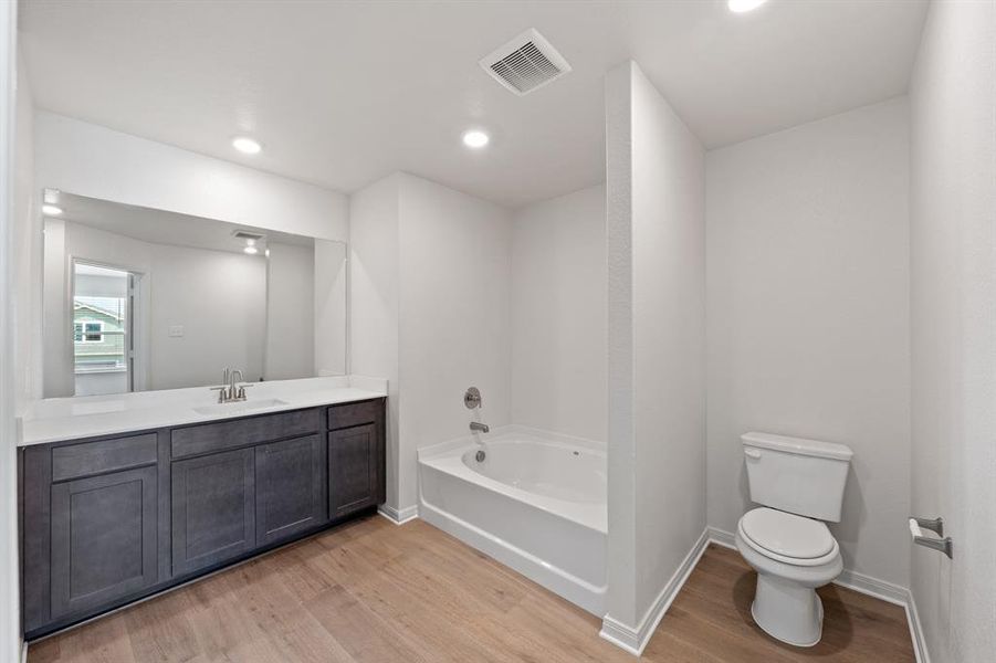 Bathroom featuring toilet, a bath, wood-style flooring, and vanity