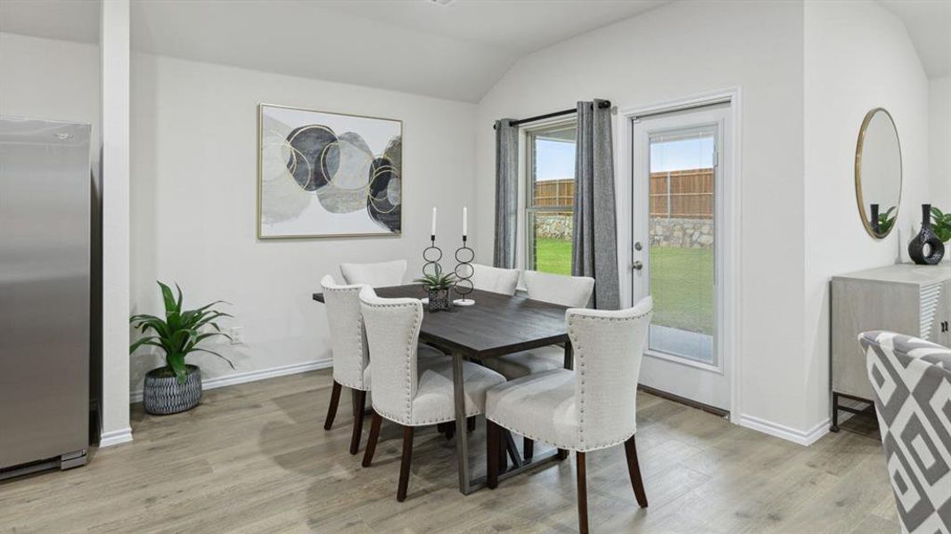 Dining area featuring light wood-type flooring and vaulted ceiling Dining area featuring light wood-type flooring and vaulted ceiling