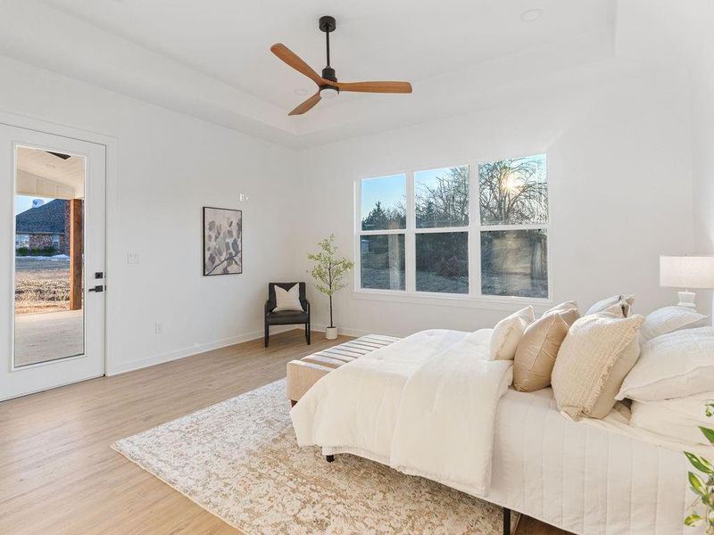 Bedroom with wood finished floors, multiple windows, ceiling fan, and access to outside