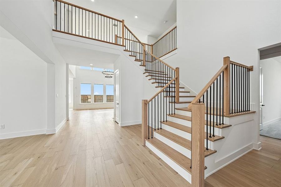 Stairway featuring a towering ceiling, wood finished floors, and recessed lighting