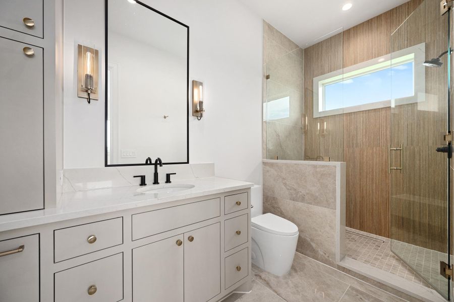 A sleek, contemporary bathroom features a spacious shower and a vanity with abundant storage.