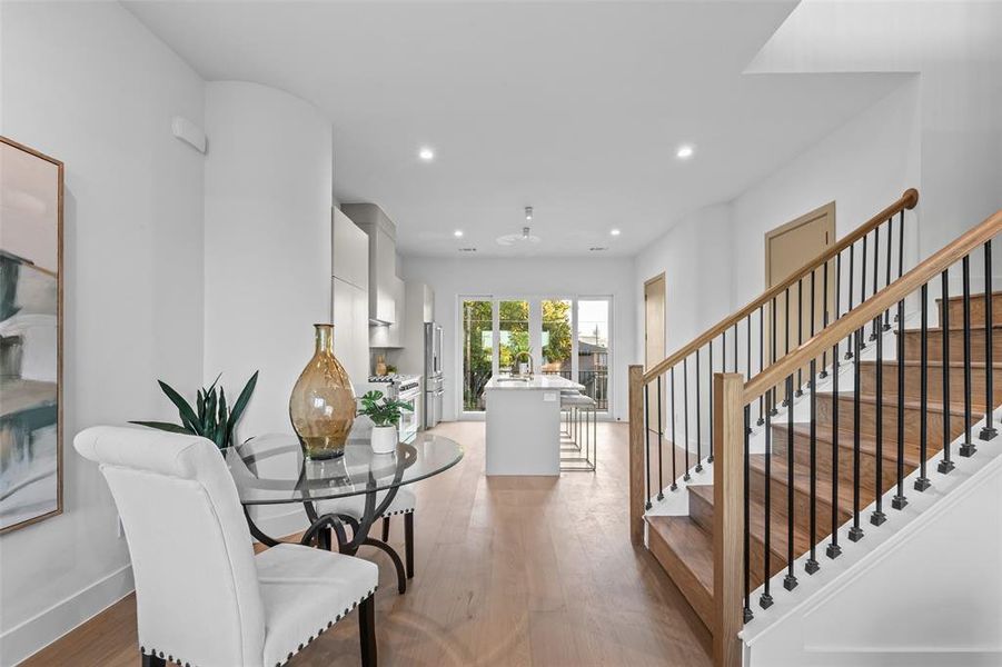 Dining room with light wood-style flooring, recessed lighting, and stairway