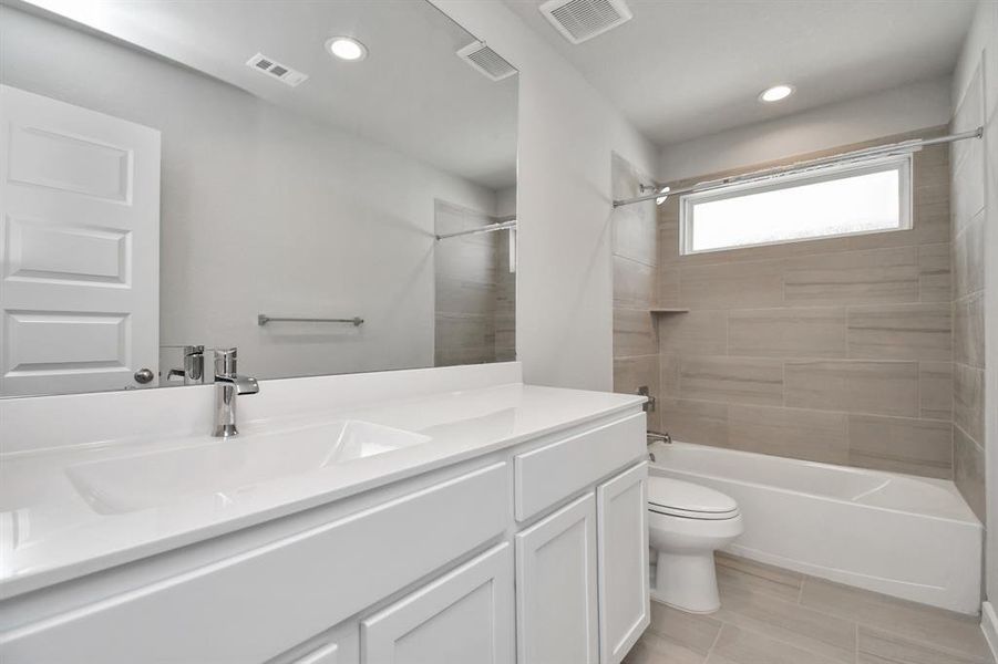 Experience sophistication in the secondary bathroom, where tile flooring complements a bath/shower combo with tile surround. Light colored cabinets complete with a beautiful light countertop, enhances the space for a truly inviting ambiance.