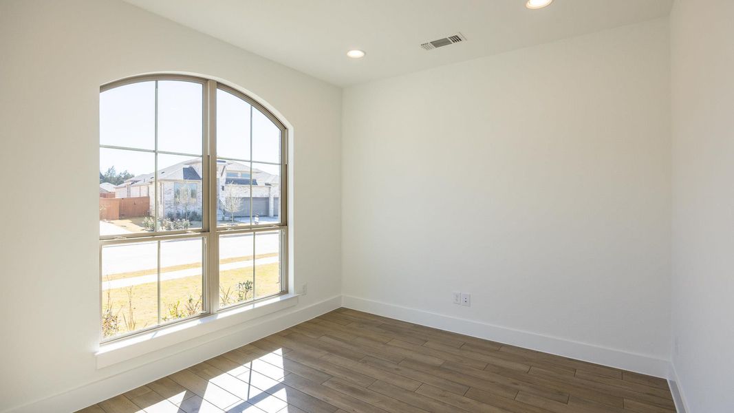 Empty room featuring dark wood-style flooring, recessed lighting, visible vents, and baseboards