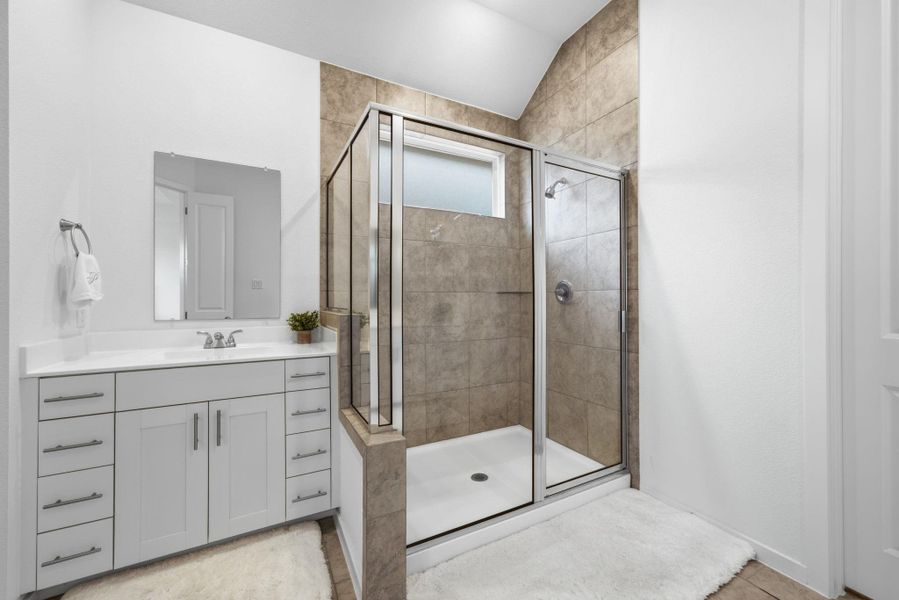 Bathroom with vanity, a shower stall, and lofted ceiling