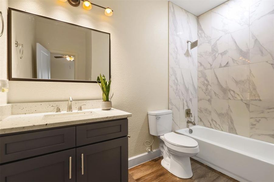 Full bathroom featuring vanity, wood-type flooring, toilet, and tiled shower / bath