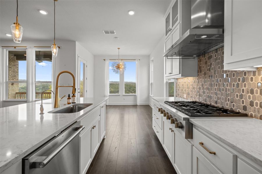 Kitchen with stainless steel appliances, dark wood finished floors, a sink, wall chimney range hood, and backsplash