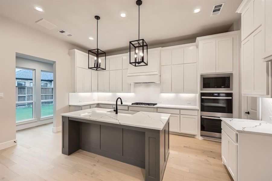 Kitchen featuring white cabinetry, a kitchen island with sink, and stainless steel appliances