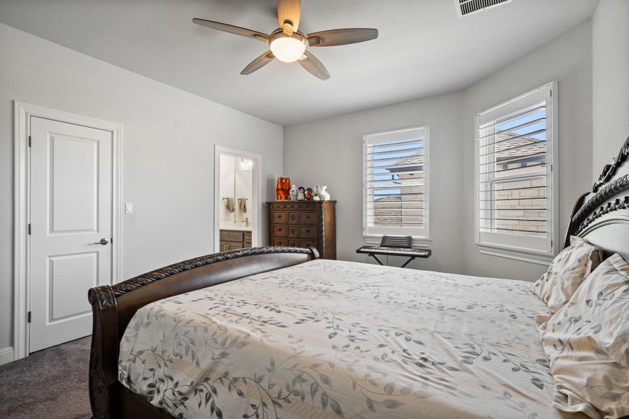 Carpeted bedroom featuring a ceiling fan and ensuite bath