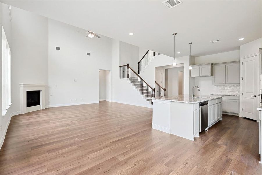 Kitchen with ceiling fan, light wood-type flooring, and a kitchen island with sink