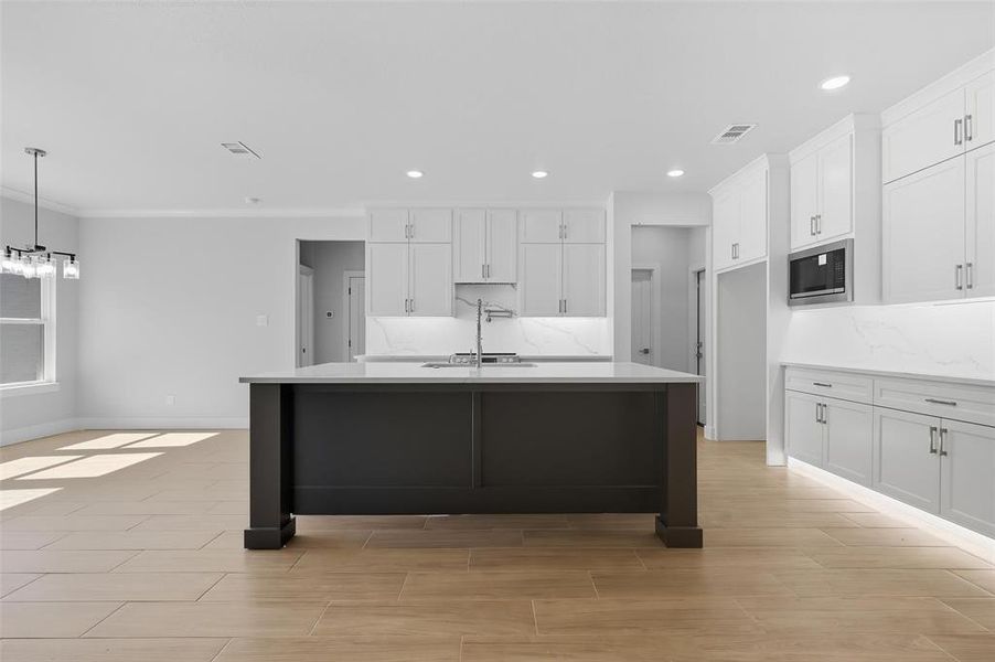 Kitchen featuring light stone counters, white cabinets, a center island with sink, recessed lighting, and a kitchen bar Kitchen featuring light stone counters, white cabinets, a center island with sink, recessed lighting, and a kitchen bar