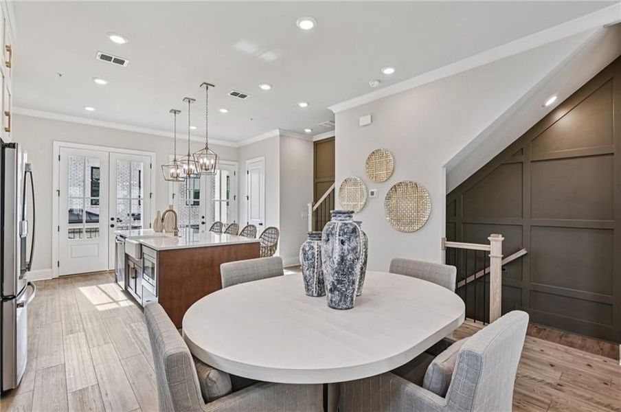 Dining space with light wood-type flooring, crown molding, recessed lighting, stairs, and a chandelier