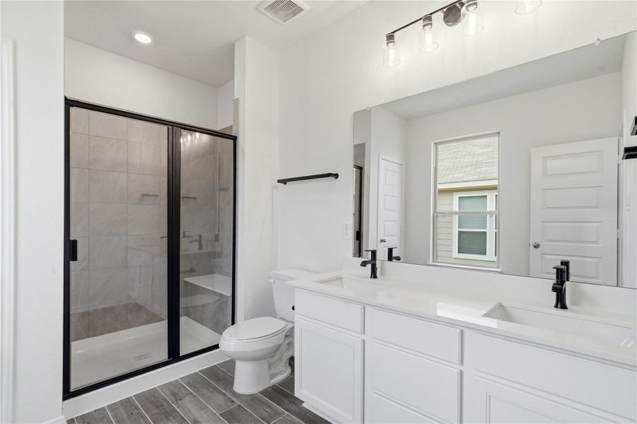 Luxurious primary suite bath boasts a large vanity with double sinks, topped with elegant countertops, a large walk-in shower with set and tile surround, and a large window for added natural lighting. Luxurious primary suite bath boasts a large vanity with double sinks, topped with elegant countertops, a large walk-in shower with set and tile surround, and a large window for added natural lighting.