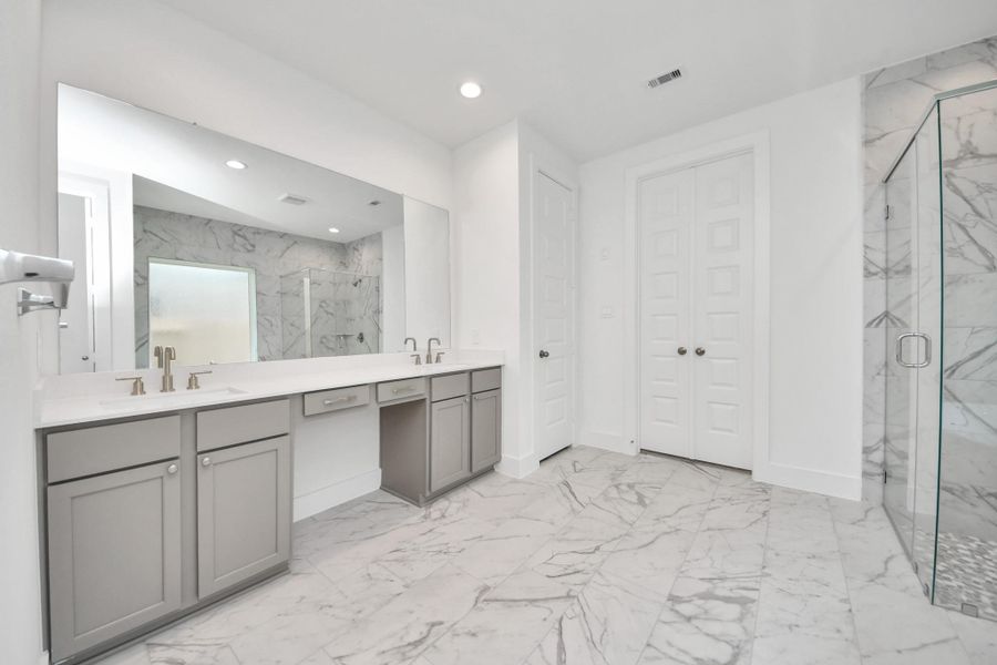 Elevate your daily routine at the elegant vanity, now equipped with double sinks, light countertops, modern hardware, and beautiful recessed lights.