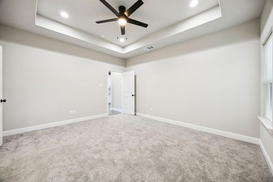 (Bedroom #1) Carpeted master bedroom room featuring a tray ceiling and a ceiling fan (Bedroom #1) Carpeted master bedroom room featuring a tray ceiling and a ceiling fan