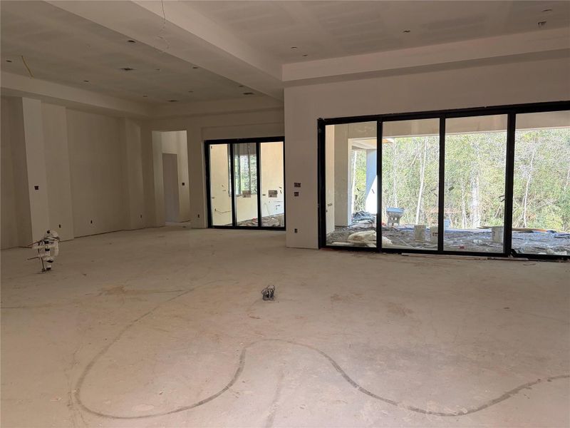 Spacious open living, kitchen, dining including massive windows and sliders overlooking covered patios and wooded acreage.