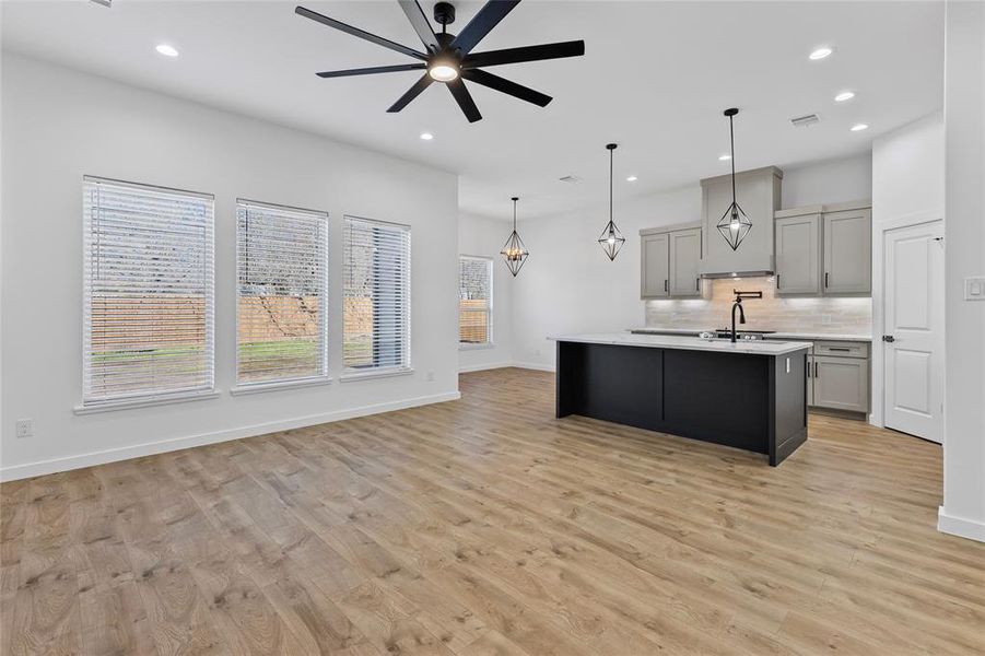 Kitchen featuring gray cabinets, ceiling fan with notable chandelier, a sink, tasteful backsplash, and light countertops