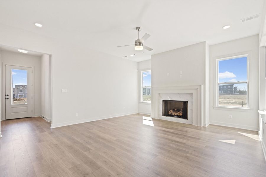 Unfurnished living room featuring a ceiling fan, a fireplace, healthy amount of natural light, light wood-type flooring, and recessed lighting