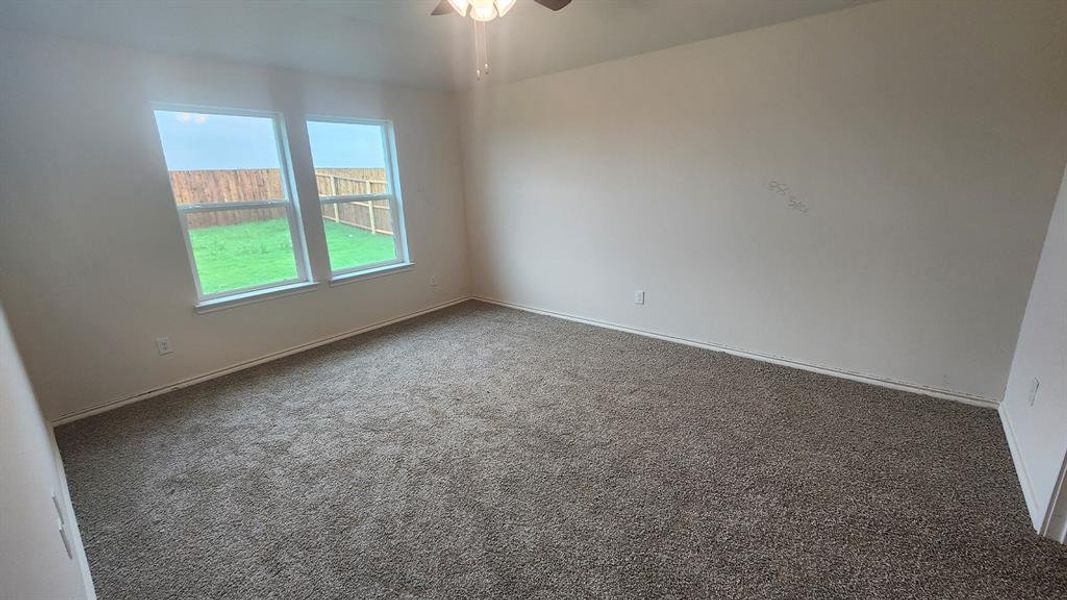 Carpeted interior room with white walls and baseboards