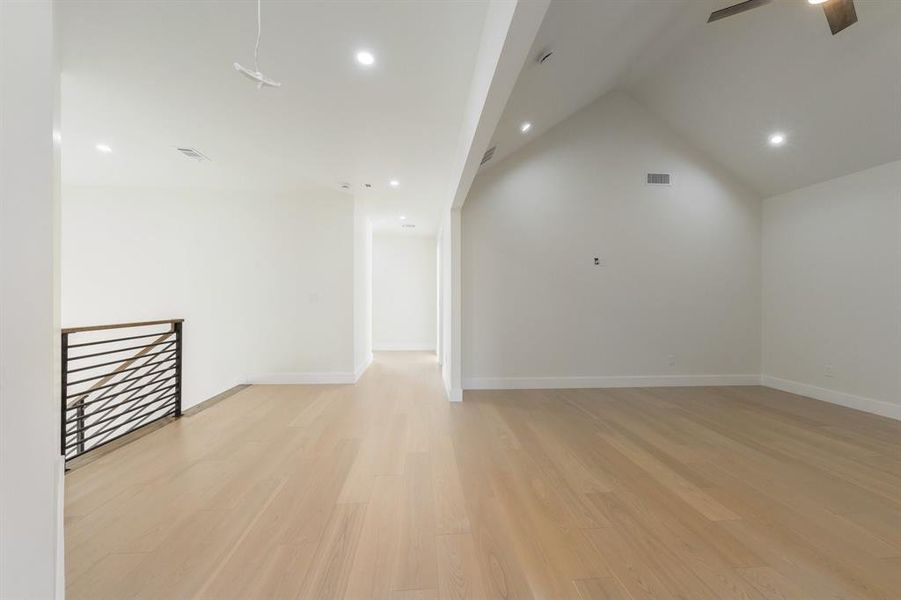 Empty room featuring light wood-style floors, recessed lighting, lofted ceiling, and ceiling fan Empty room featuring light wood-style floors, recessed lighting, lofted ceiling, and ceiling fan