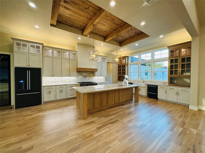 Kitchen with a center island, wood ceiling, light wood-type flooring, and black fridge