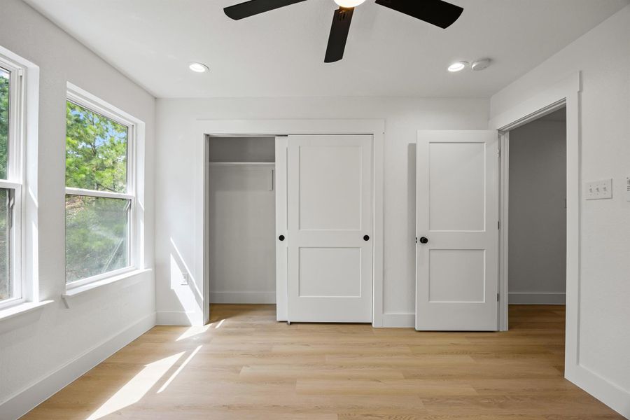 Unfurnished bedroom with multiple windows, a closet, light wood finished floors, and recessed lighting Unfurnished bedroom with multiple windows, a closet, light wood finished floors, and recessed lighting