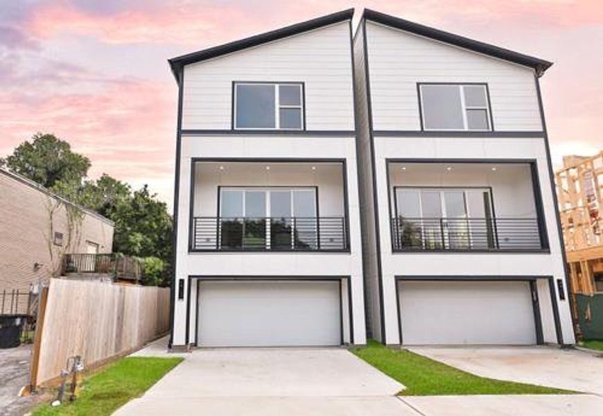 Modern 4-story home featuring a sleek design with two balconies and a double garage, set against a beautiful sky at dusk.