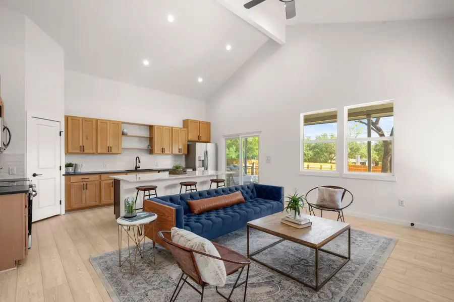 Living area featuring high vaulted ceiling, beam ceiling, light wood-type flooring, recessed lighting, and a ceiling fan