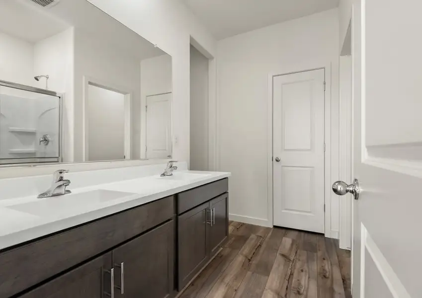 The master bathroom has spacious countertops and a glass-enclosed shower.